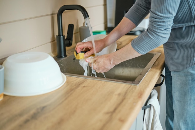 Unrecognizable man washing dishes in sink at a kitchen