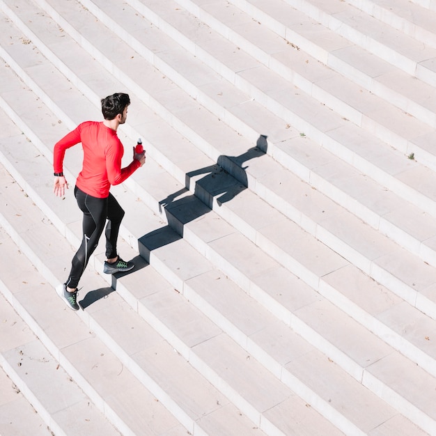 Unrecognizable man with bottle running upstairs