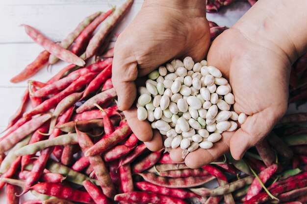 Unrecognizable mans hands holding a handful of white beans over a table full of bean shells