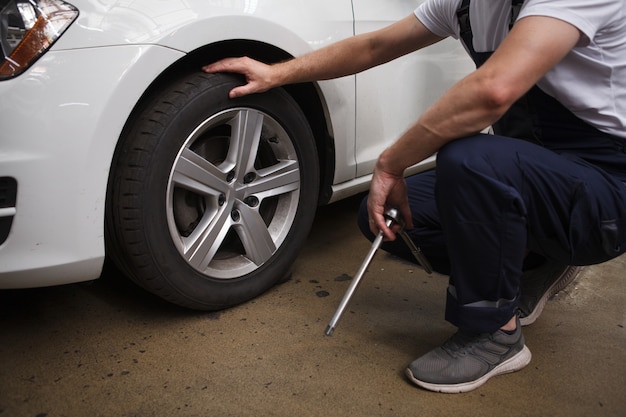 Unrecognizable mechanic examining car wheels