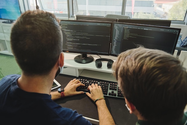 Unrecognizable men writing program code together