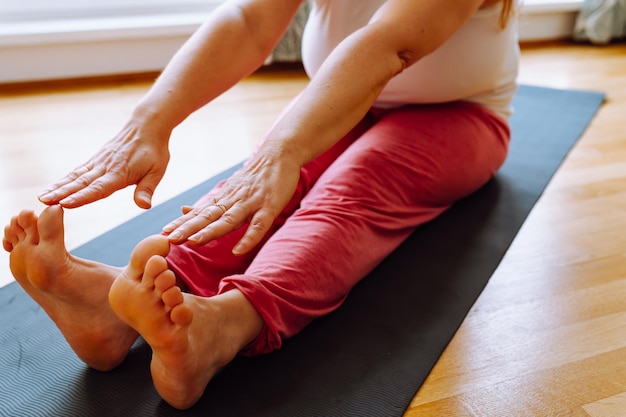 unrecognizable middle-aged woman of full physique performs stretching exercises at home