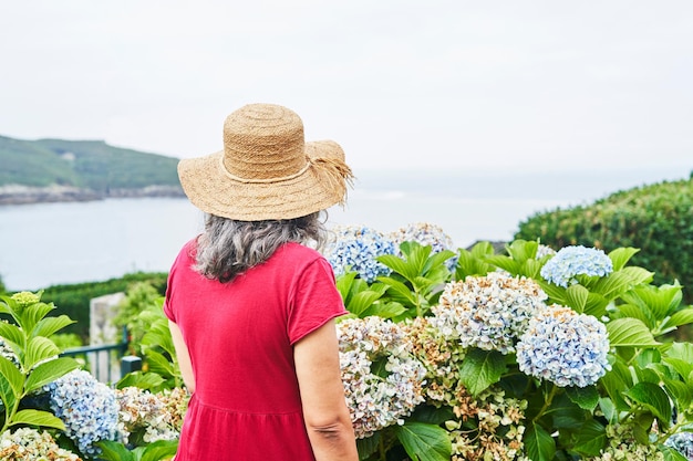 Unrecognizable middle-aged woman in red dress watching the sea