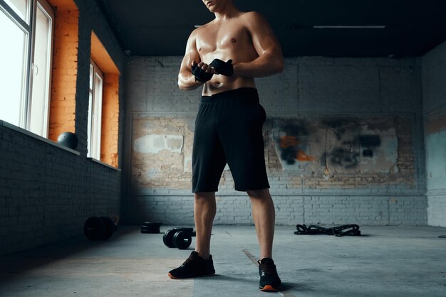 Photo unrecognizable muscular man wearing sport gloves while standing in gym