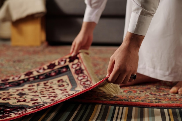 Unrecognizable muslim man placing prayer mat on floor