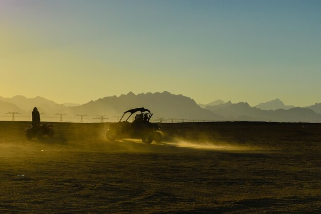 Unrecognizable people driving buggy during safari trip at sunset in Arabian desert not far from the Hurghada city Egypt