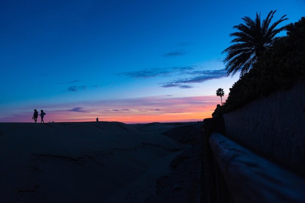 Unrecognizable people walking in the dark viewing the sunset