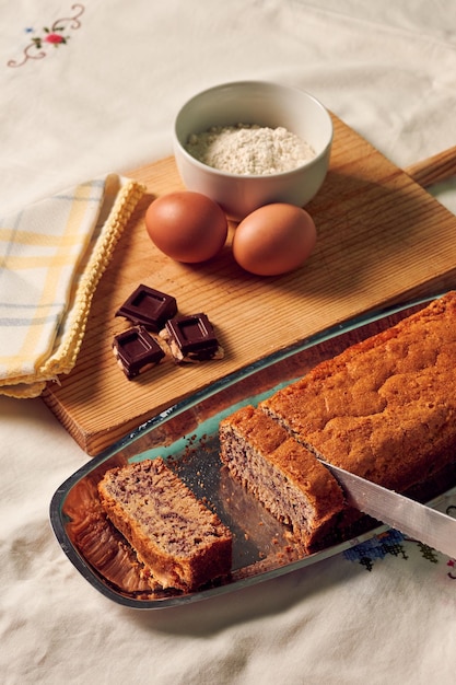 Unrecognizable person with a knife cuts a sponge cake with some ingredients on a white tablecloth