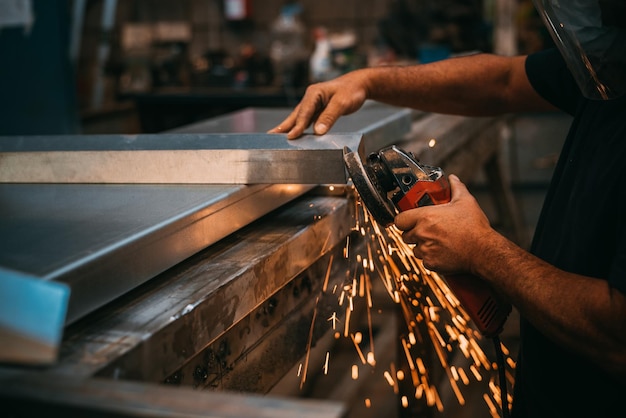 Photo unrecognizable person working in a workshop cutting metal sparks are seen