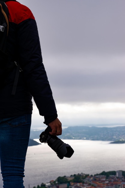 Unrecognizable photographer with camera in hand and in the background the city of Bergen and the fjord in Norway