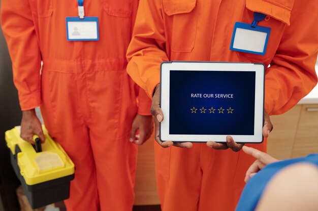 unrecognizable plumber or serviceman holding tablet with rating scheme and asking customer to rate their service