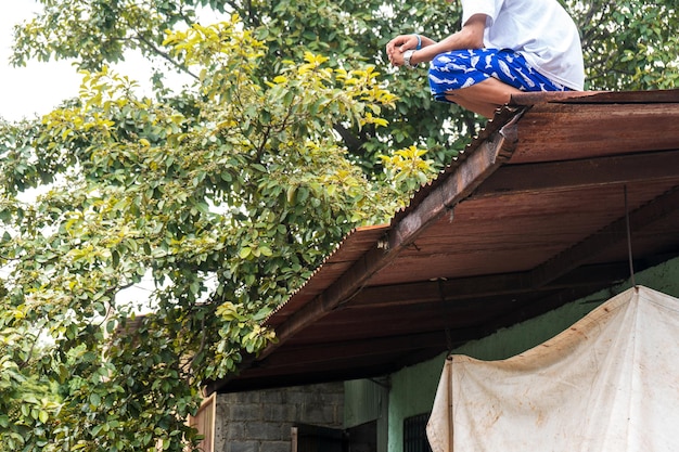 Unrecognizable poor teenager on the roof of his dwelling