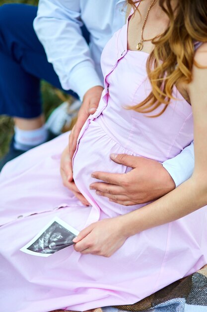 Unrecognizable pregnant couple holding ultrasound scan