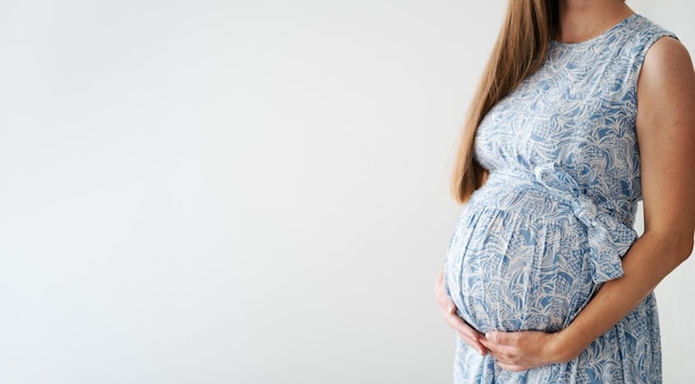 Неузнаваемая беременная женщина гладит животик ребенка в красивом синем платье в одежде на светло-сером фонеСчастливая здоровая стильная модная беременность