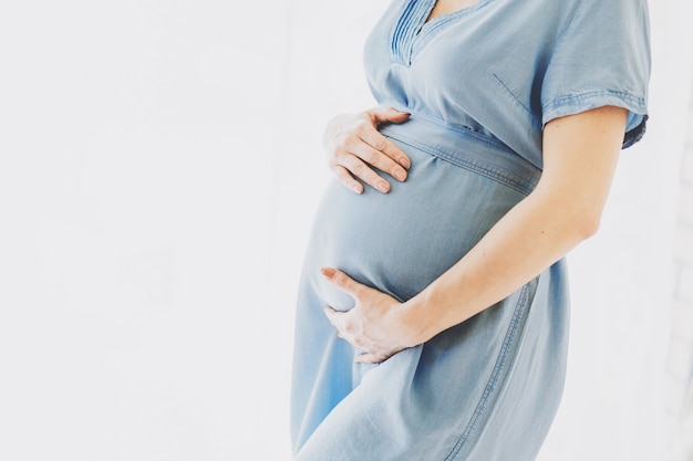 Unrecognizable Pregnant woman touching belly being home enjoying pregnancy. Lifestyle. Maternity concept.