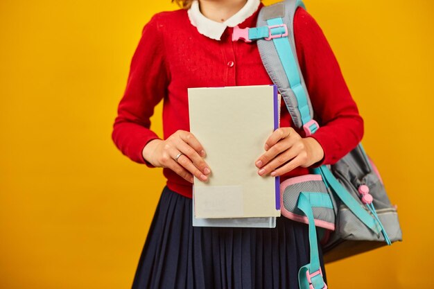 Unrecognizable Schoolgirl with backpack headphone and books in hand back to school