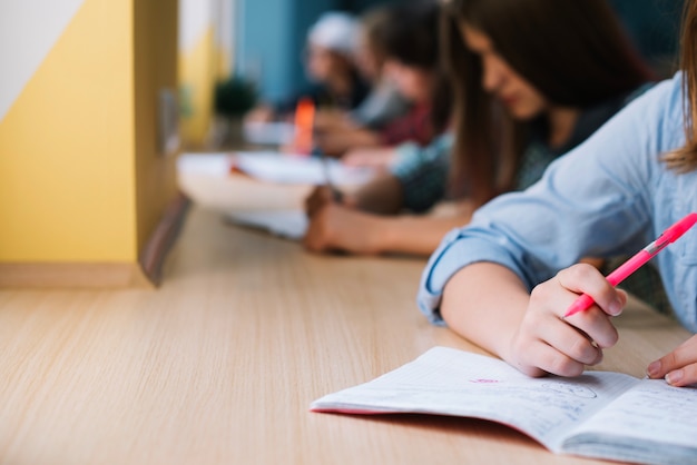 Photo unrecognizable schoolgirl writing in notepad