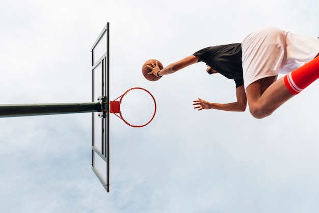 Uomo sportivo irriconoscibile che getta la pallacanestro nella rete