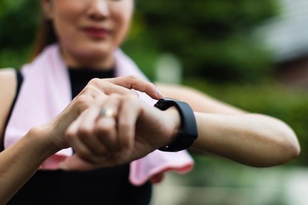 Le donne sportive irriconoscibili in abbigliamento sportivo alzano la mano e usano il dito per regolare l'impostazione dell'applicazione nello smartwatch al polso per controllare il risultato dopo l'allenamento o l'esercizio concetto di buona assistenza sanitaria