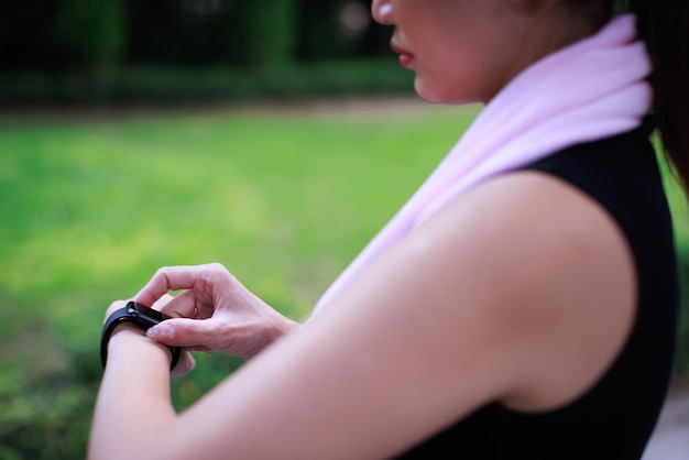 Le donne sportive irriconoscibili in abbigliamento sportivo alzano la mano e usano il dito per regolare l'impostazione dell'applicazione nello smartwatch al polso per controllare il risultato dopo l'allenamento o l'esercizio concetto di buona assistenza sanitaria