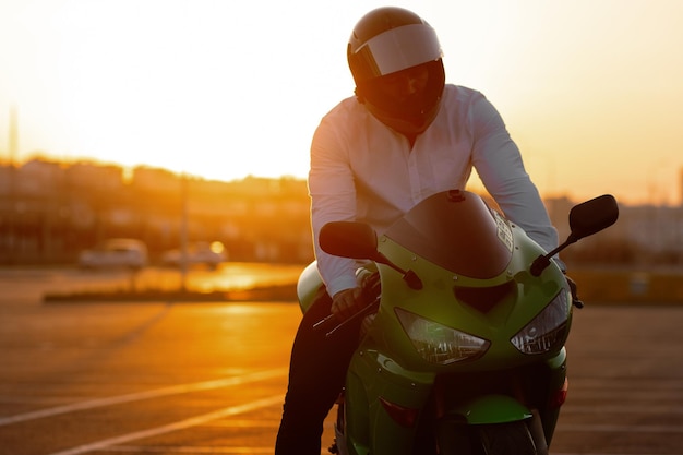 Unrecognizable stylish male motorcyclist in helmet sitting on parked motorbike in city