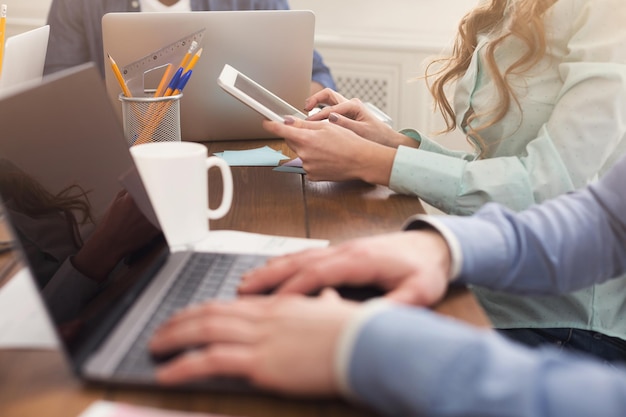 Unrecognizable team of young businesspeople working on laptop, typing on computer, copy space