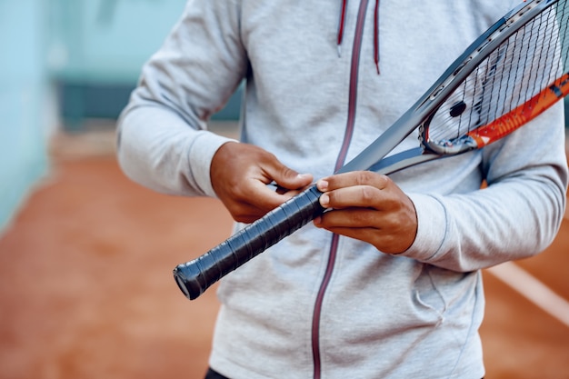 Фото До неузнаваемости теннисист ремонтирует покрытие ручки теннисной ракетки крупным планом