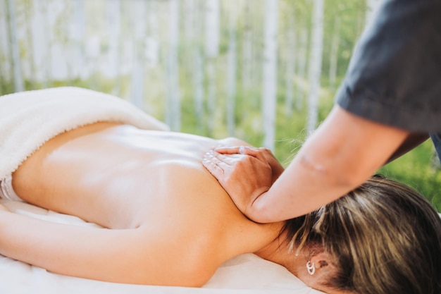 Unrecognizable therapist making a back and neck massage to a face down female patient