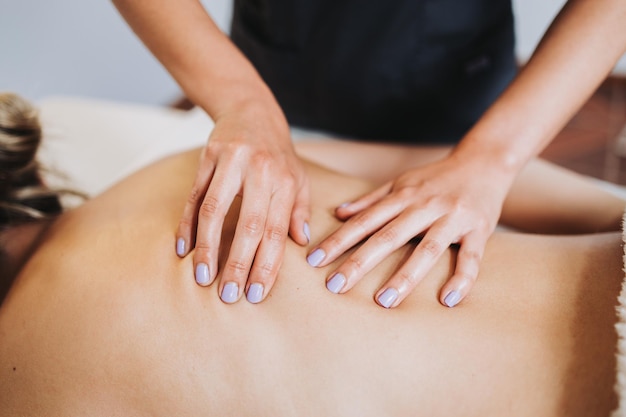 Неузнаваемый терапевт делает массаж спины и позвоночника пациентке Расслабление и снятие стресса