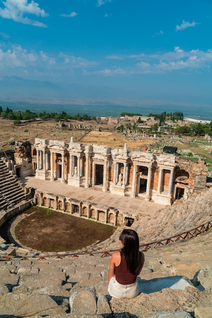 Unrecognizable tourist sitting on her back enjoying the view of the famous theater of Hierapolis in Pamukkale