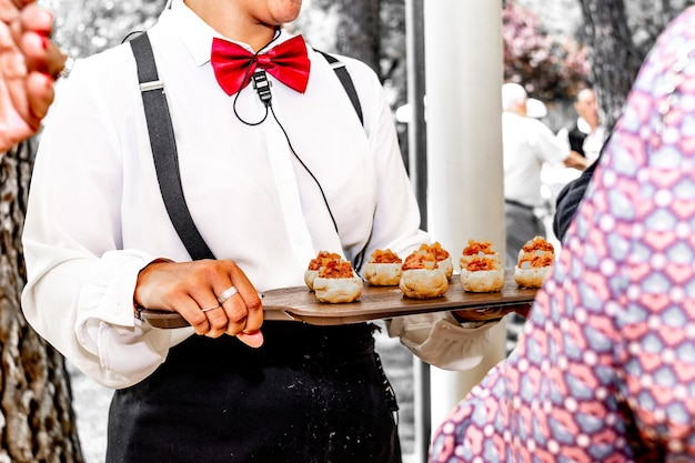 Una cameriera irriconoscibile che offre tartine o stuzzichini su un vassoio a un matrimonio o un evento