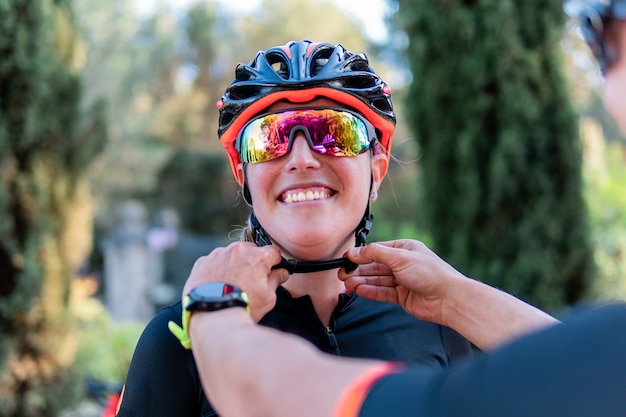 Photo unrecognizable white man fastening the bicycle helmet of a young caucasian cyclist