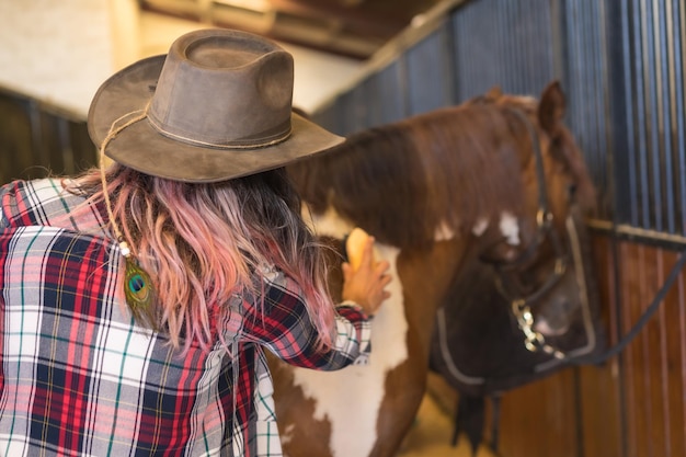 写真 安定した、アメリカ南部の帽子とジーンズで馬を磨いている認識できない女性、垂直写真