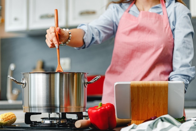 Unrecognizable woman cooking something near the stove in kitchen close up photo