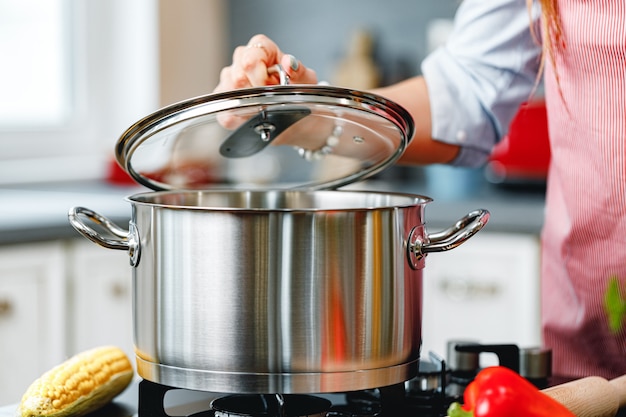 Unrecognizable woman cooking something near the stove in kitchen close up