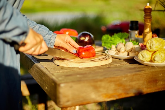 Unrecognizable woman cutting fresh pepper vegetables on wooden board