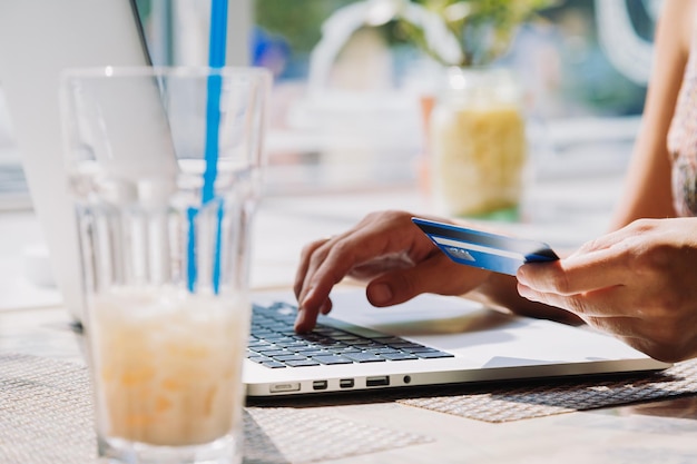 카페에서 노트북을 사용하여 신용 카드로 온라인 쇼핑을 하는 알아볼 수 없는 여성