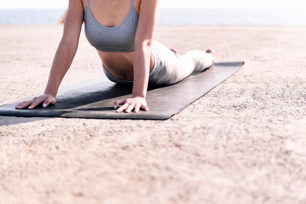 Unrecognizable woman doing yoga by the sea