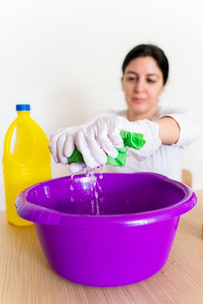 Unrecognizable woman draining a wipe cloth with bleach in order to disinfect the house.