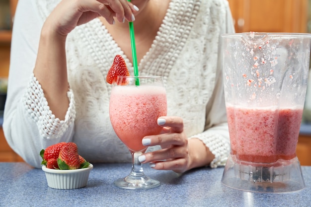 Foto donna irriconoscibile che beve un frullato sano fatto con latte di mandorle e fragole