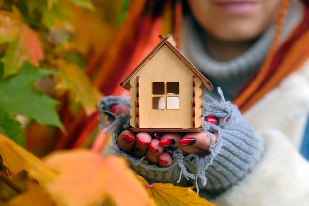 Unrecognizable woman holding small wooden house Body part of female with toy house Concept of purchasing new apartment roof overhead