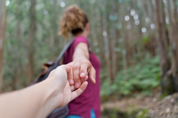 Donna irriconoscibile che raggiunge la mano alla macchina fotografica nella foresta. vista orizzontale del viaggiatore zaino in spalla in montagna. persone e concetto di destinazione di viaggio.