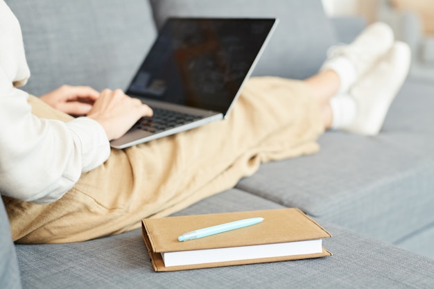 사진 인식 할 수없는 여자는 집에서 소파에 편안하게 앉아 그녀의 노트북, 가로 샷에서 작업