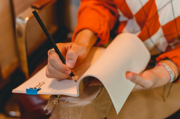 unrecognizable woman sitting writing on blank notepad copy space