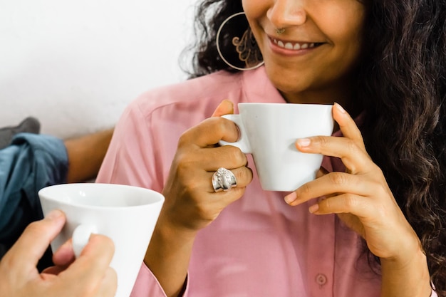 Unrecognizable woman smiling and having a cup of coffee with her partner.