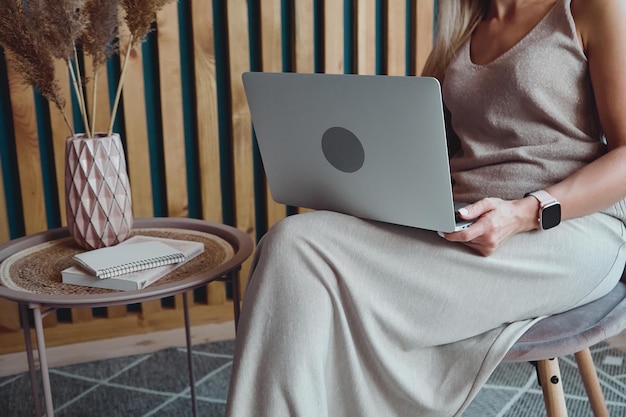 Unrecognizable woman using laptop sitting on chair at home office