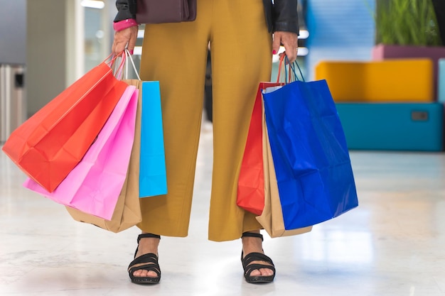 Unrecognizable woman with colorful shopping bags in the mall