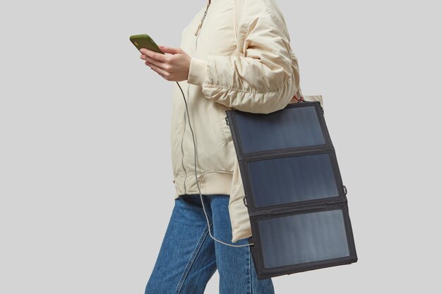 Photo unrecognizable woman with flexible solar battery holding smartphone