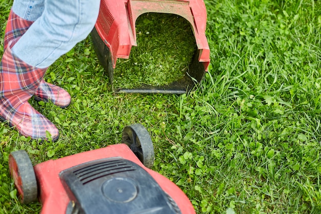 Unrecognizable Woman with a lawn mower grass at home garden, gardener woman working, Beautiful summer landscape, sunlight, great design for any purposes, gardening concept