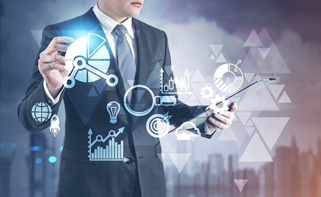 Unrecognizable young businessman is looking at his clipboard and holding a glowing marker. A HUD and triangles in the foreground. Toned image double exposure